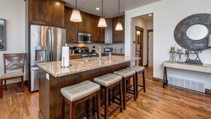 Eine moderne Küche mit Holzschränken, Edelstahlgeräten und einer Arbeitsplatte aus Granit.