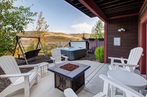Eine Terrasse im Freien mit Adirondack-Stühlen, einem Whirlpool und einer Feuerstelle.