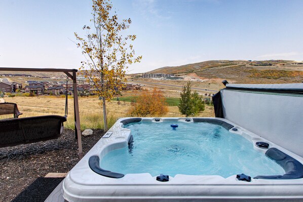 A hot tub with a clear view of a residential area and hills in the background.