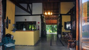 Uma área de recepção com balcão, cadeiras e um candelabro.