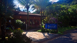 Um hotel com telhado de azulejos, rodeado por vegetação exuberante e palmeiras.