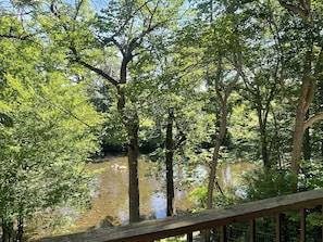 Una terraza de madera con vista a un río tranquilo y árboles al fondo.
