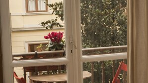 A view through a window with a table and chairs, a building with a balcony, and a plant. - The best B&b in town (Torino)