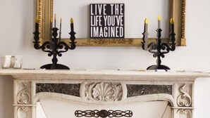 A fireplace with ornate white mantel and gold accents, a candelabra with lit candles, and a motivational sign above. - The best B&b in town (Torino)
