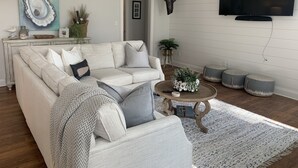 Un salon comprenant un canapé, une table basse, des poufs, un téléviseur et des objets de décoration.
