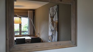Un comedor con una mesa, sillas y una lámpara. En la pared se ve un cuadro grande de un ciervo.