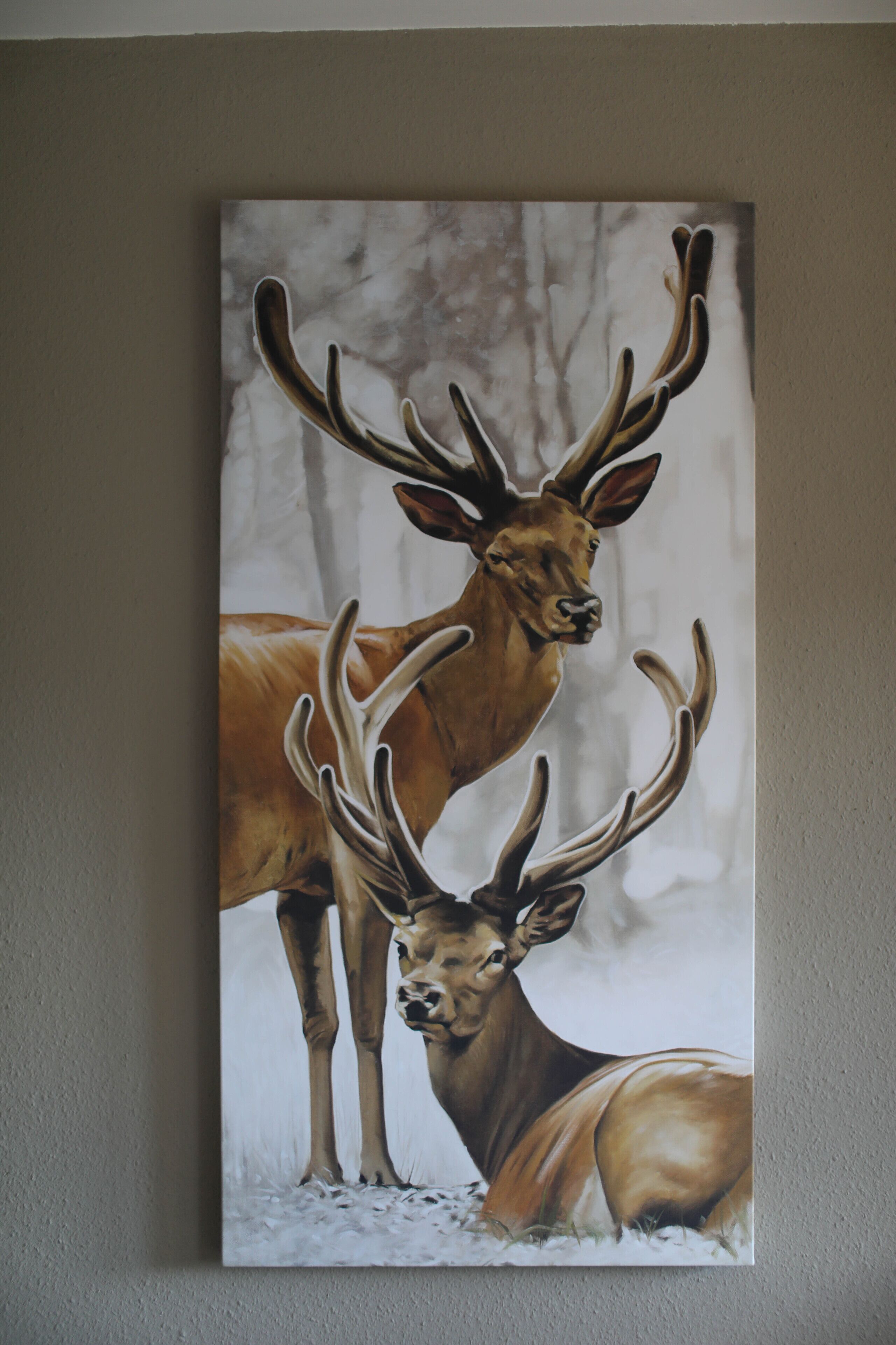 Un tableau représentant deux cerfs dans un paysage enneigé.