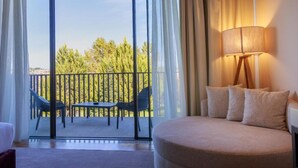 A hotel room with a balcony, a sofa, a table, and a lamp. - Olive Nature - Hotel & SPA (Valpacos)