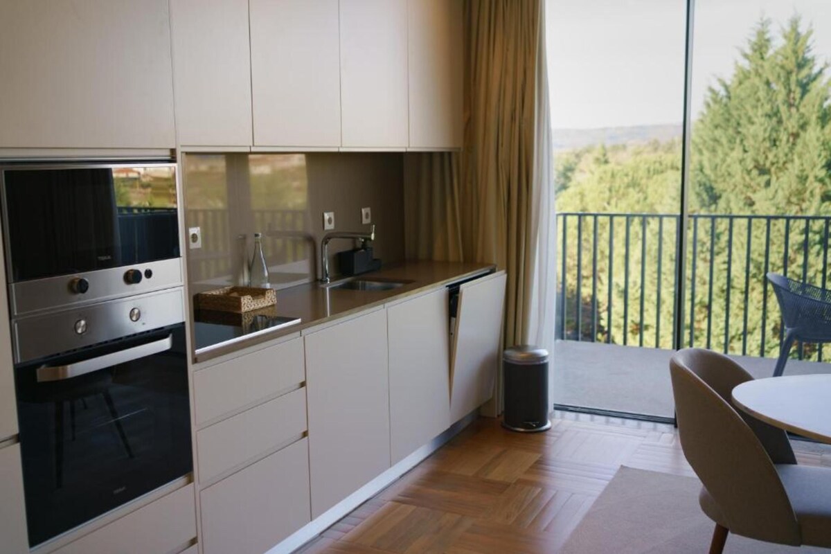 A modern kitchen with a built-in oven, a sink, and a small trash can.