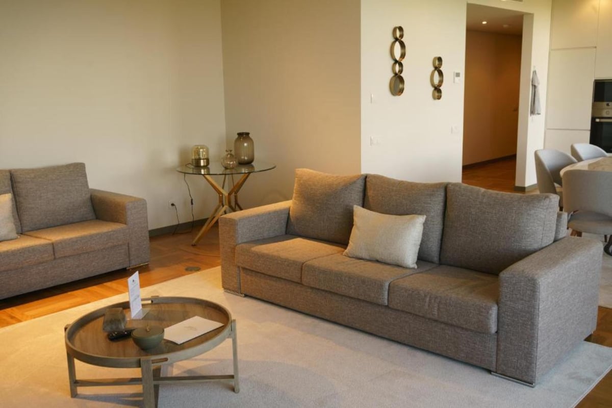 A modern living room with two grey sofas, a glass coffee table, and a small side table.