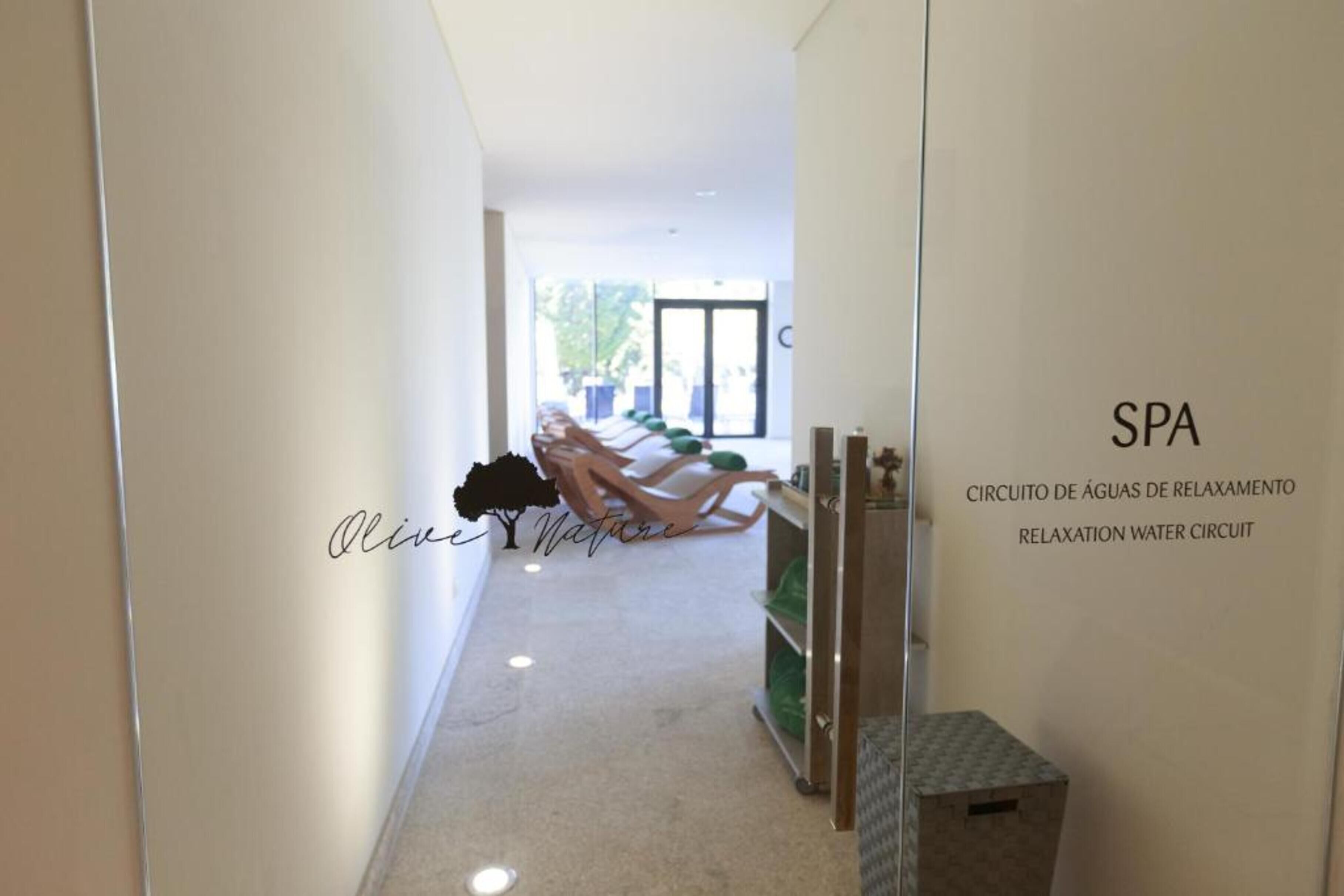 A spa area with a relaxation water circuit, a reception desk, and a view of the outdoors.