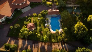 An aerial view of a residential property with a swimming pool, multiple buildings, and surrounding greenery. - Olive Nature - Hotel & SPA (Valpacos)