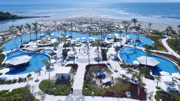 Un complexe hôtelier doté de plusieurs piscines, de palmiers et offrant une vue sur la plage.