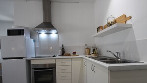 Una cocina moderna con armarios blancos, horno empotrado, microondas, campana extractora de acero inoxidable y un lavamanos doble.