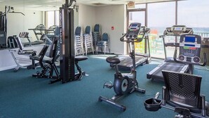 Une salle de sport équipée de divers appareils pour le cardio et le renforcement musculaire, notamment des tapis de course, des vélos d’appartement et des appareils de musculation.