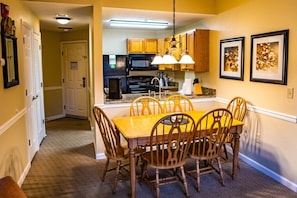 Enjoy meals in this cozy dining area with a table and chairs, adjacent to a modern kitchen and hallway.