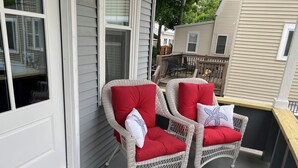Two wicker chairs with red cushions on a porch. - Quaint Cottage Vacation (Old Orchard Beach)
