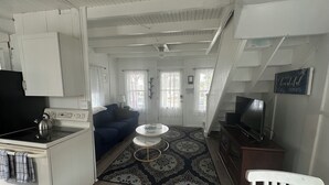 A compact living space with a kitchenette, a sofa, a television, and a staircase. - Quaint Cottage Vacation (Old Orchard Beach)