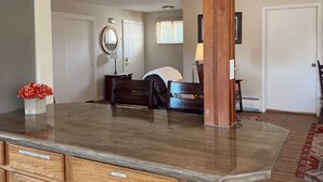 A kitchen with wooden cabinets, a marble countertop, and a built-in sink. - Spacious Upstairs Loft (Miles City)