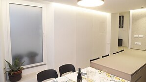 Un comedor moderno con una mesa preparada para cuatro, una planta en maceta y un ventanal grande.
