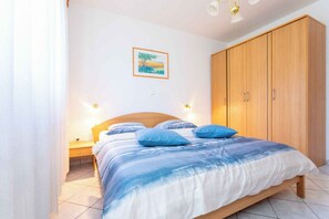 Quarto com cama, guarda-roupa de madeira e mesa de cabeceira.