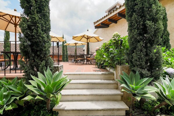 A patio area with outdoor seating, steps leading up to the entrance, and various plants.