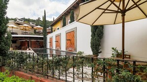 Ein Innenhof mit Pool, Sitzgelegenheiten im Freien und einem weißen Gebäude mit Holztüren.