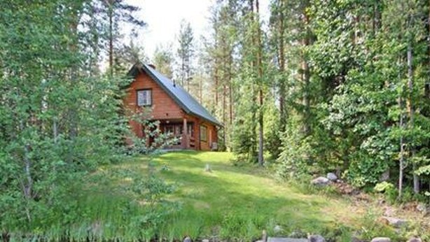 A cabin with a wooden deck leading to a pond surrounded by dense forest. - Honkatupa by Interhome (Ruovesi)