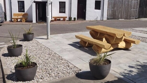 A building with a white facade and a black roof, a wooden bench, and a picnic table. - 4-bed Cottage in Portknockie, Near Cullen, Moray (Buckie)