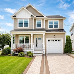 A two-story house with a front porch, a garage, and a well-maintained lawn.