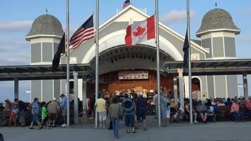 A covered outdoor area with a stage and audience seating, flags, and a clear sky.
