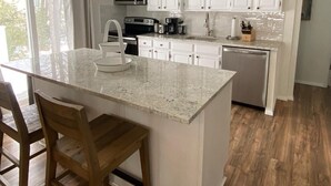 A modern kitchen with white cabinets, a large island with a sink, and a microwave above the counter.