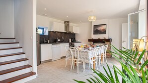 A modern kitchen with white cabinets, a dining area with a table set for four, and a staircase leading to another level.