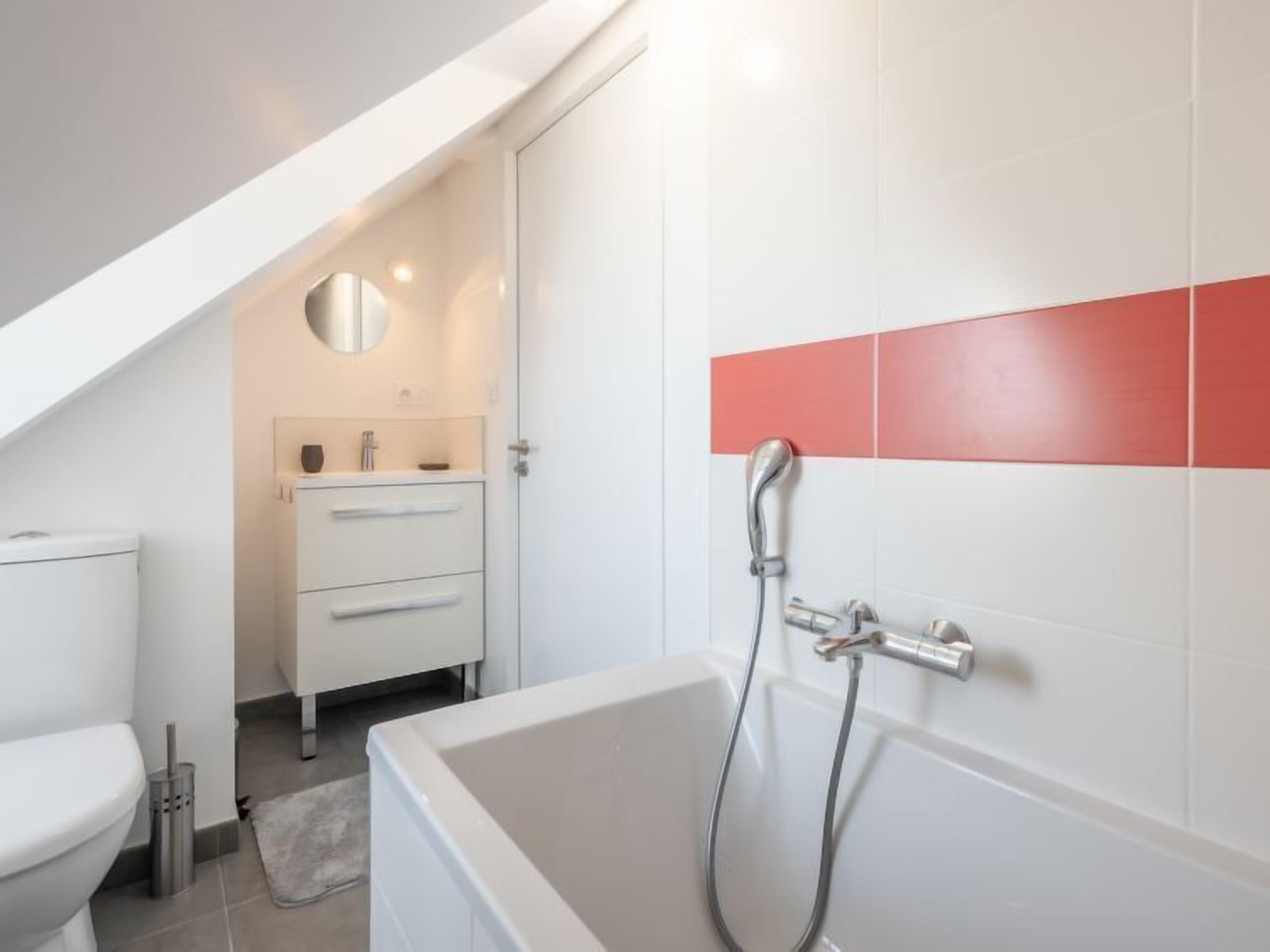 Un bagno moderno con vasca, servizi igienici e un mobile bagno con cassetti.