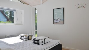 Ein Schlafzimmer mit einem Bett, einem Fenster, einem gerahmten Bild und einem Wandpinnbrett.