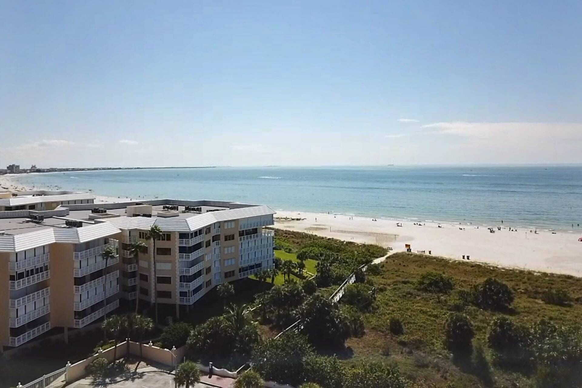 Un hotel frente a la playa con varios pisos, una playa de arena y una vista despejada del océano.