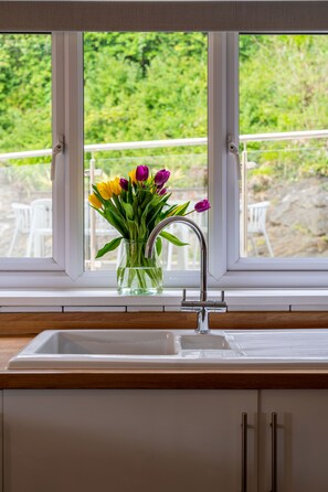 A kitchen with a window, a sink, and a vase with flowers.