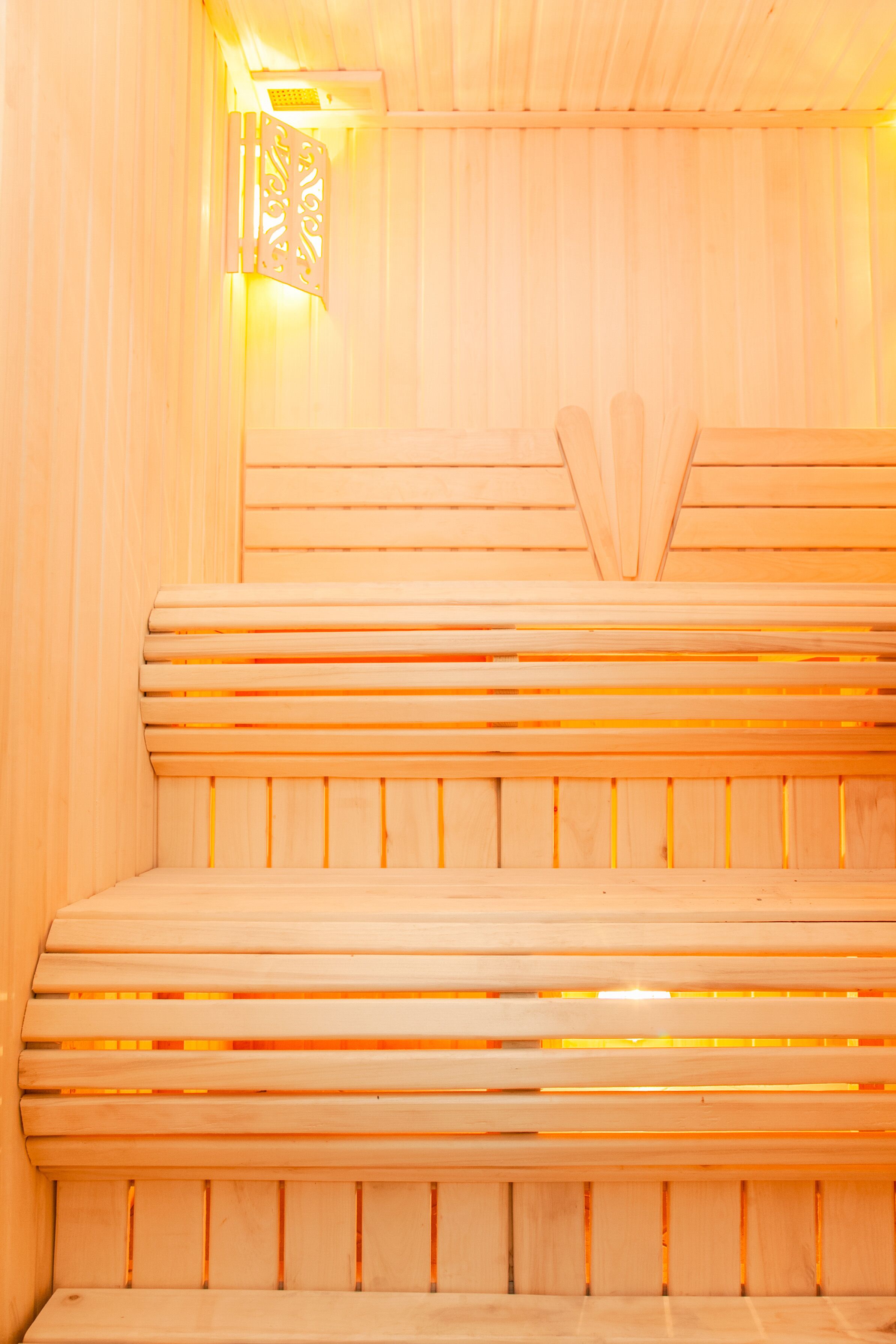 A wooden sauna with benches and a wall-mounted light fixture.