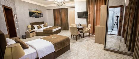 Habitación de hotel con dos camas, un escritorio, una silla, un televisor y un espejo.