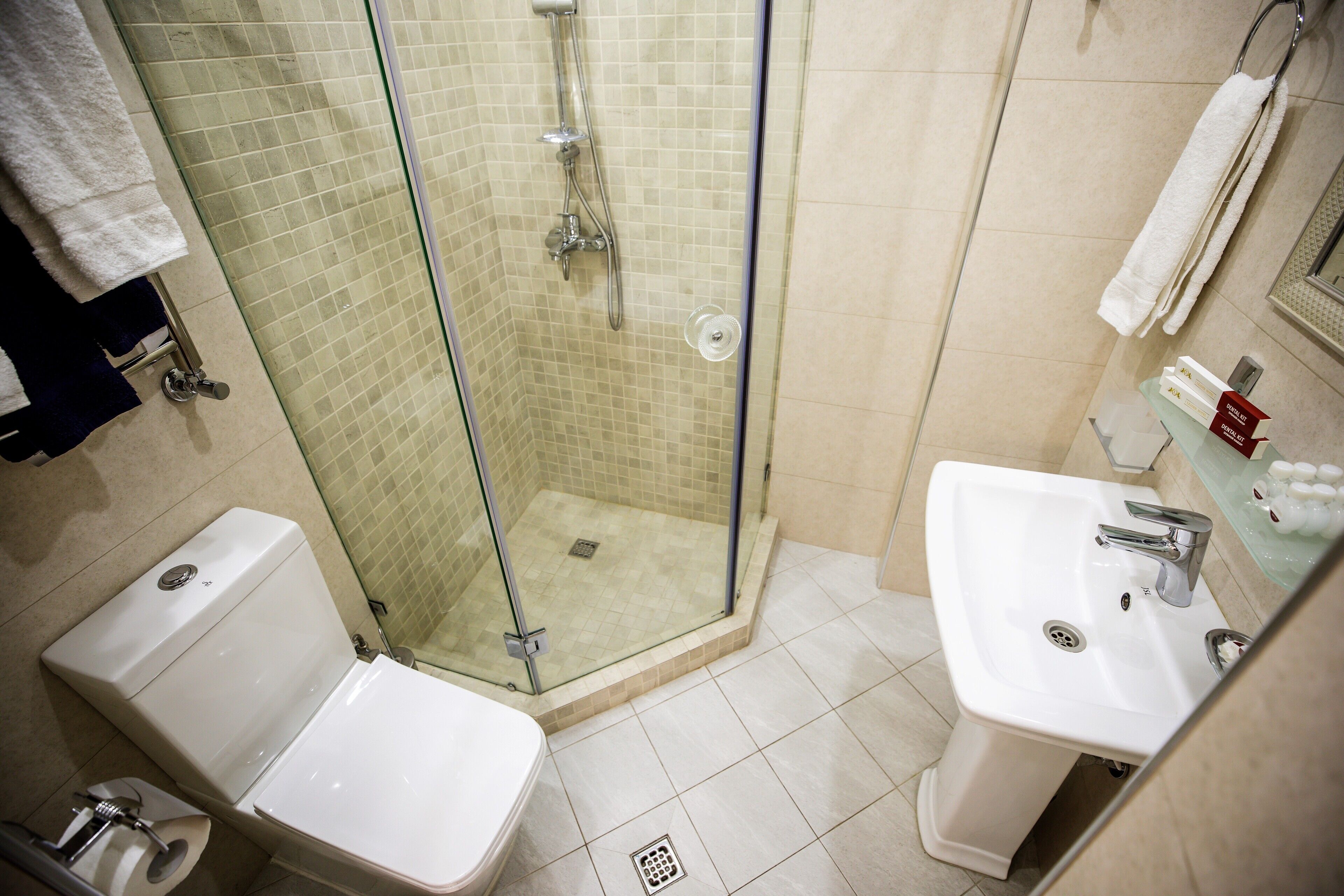 A bathroom with a glass-enclosed shower, a toilet, and a sink.