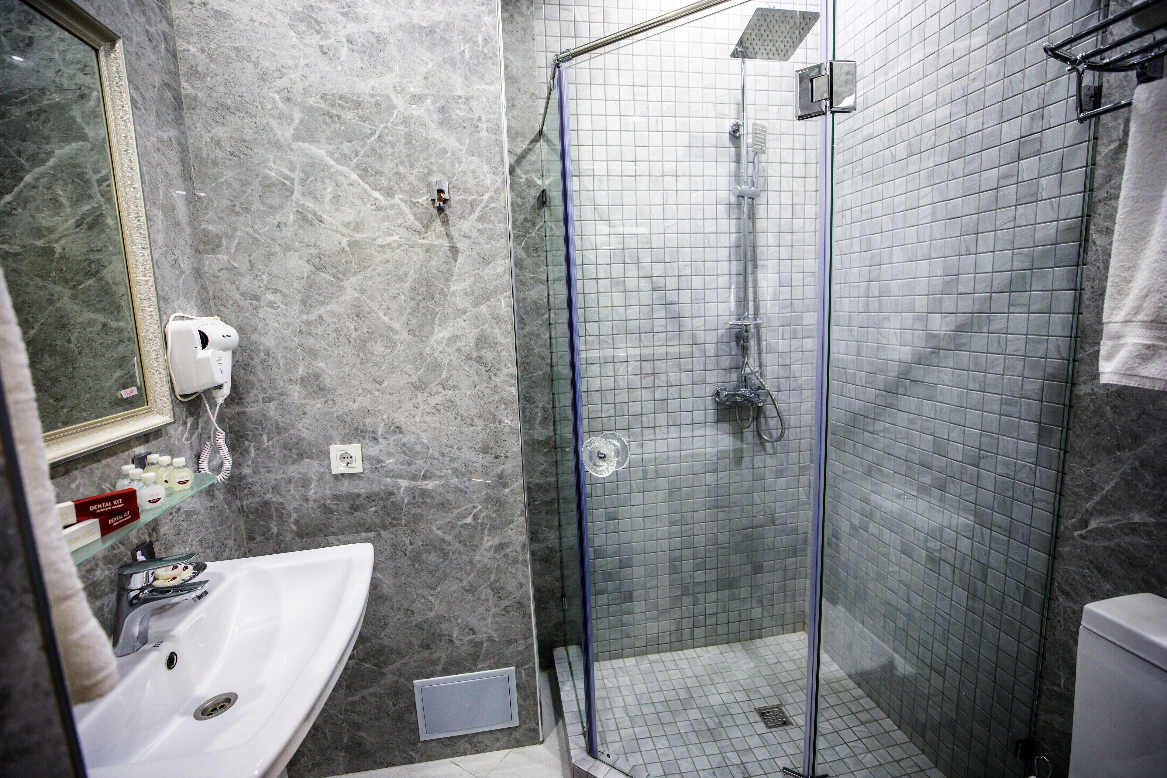 A bathroom with a sink, mirror, and shower.