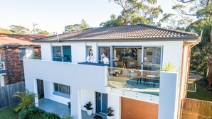 A modern two-story house with a balcony, a garage, and a well-maintained garden.