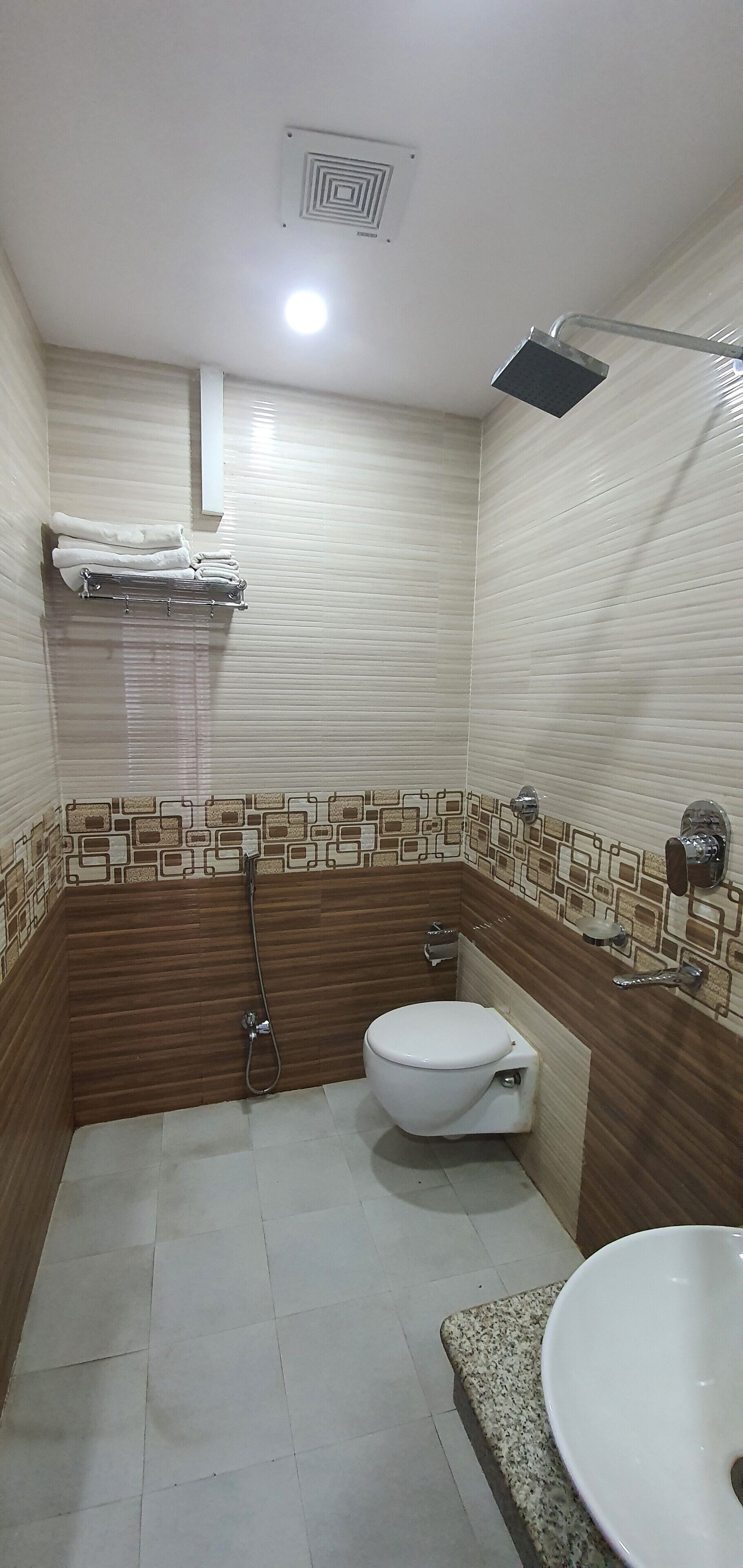 Un baño con inodoro, lavamanos, ducha y toallero.