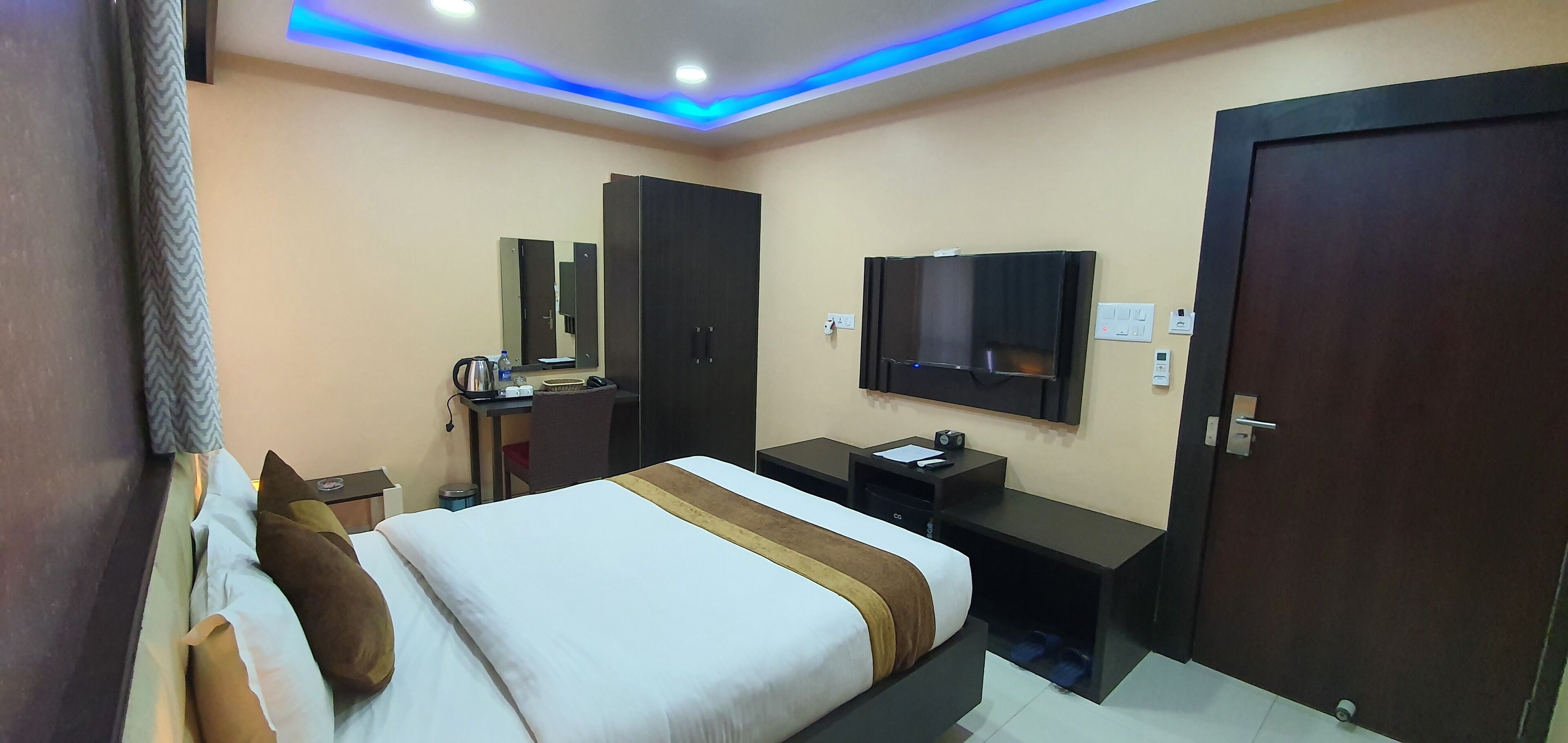 A hotel room with a bed, a desk, a TV, and a wardrobe.