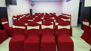 Rows of red chairs with white sashes, arranged in a conference room.