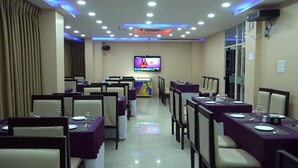A conference room with tables set for meetings, a television screen, and a large window.