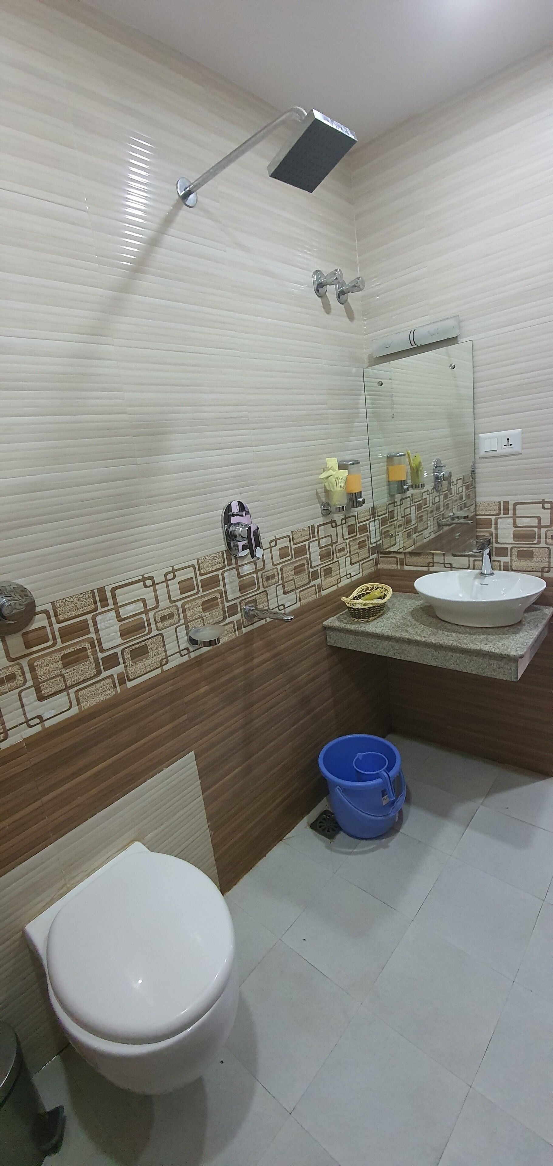 A bathroom with a toilet, a sink, a shower, and a mirror.