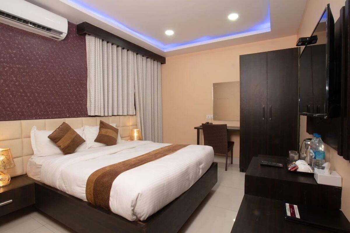 Ein modernes Hotelzimmer mit einem großen Bett, einem Schreibtisch, einem Fernseher und einer Klimaanlage.