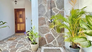 Un patio empedrado con ducha, plantas en macetas y una puerta de madera.