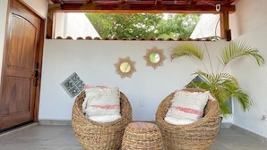 Un patio cubierto con mobiliario de mimbre y una planta en maceta.